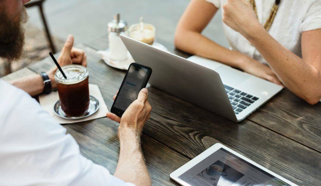 Two people working in a casual office with devices and coffee on the table which represents personalization of email communication.