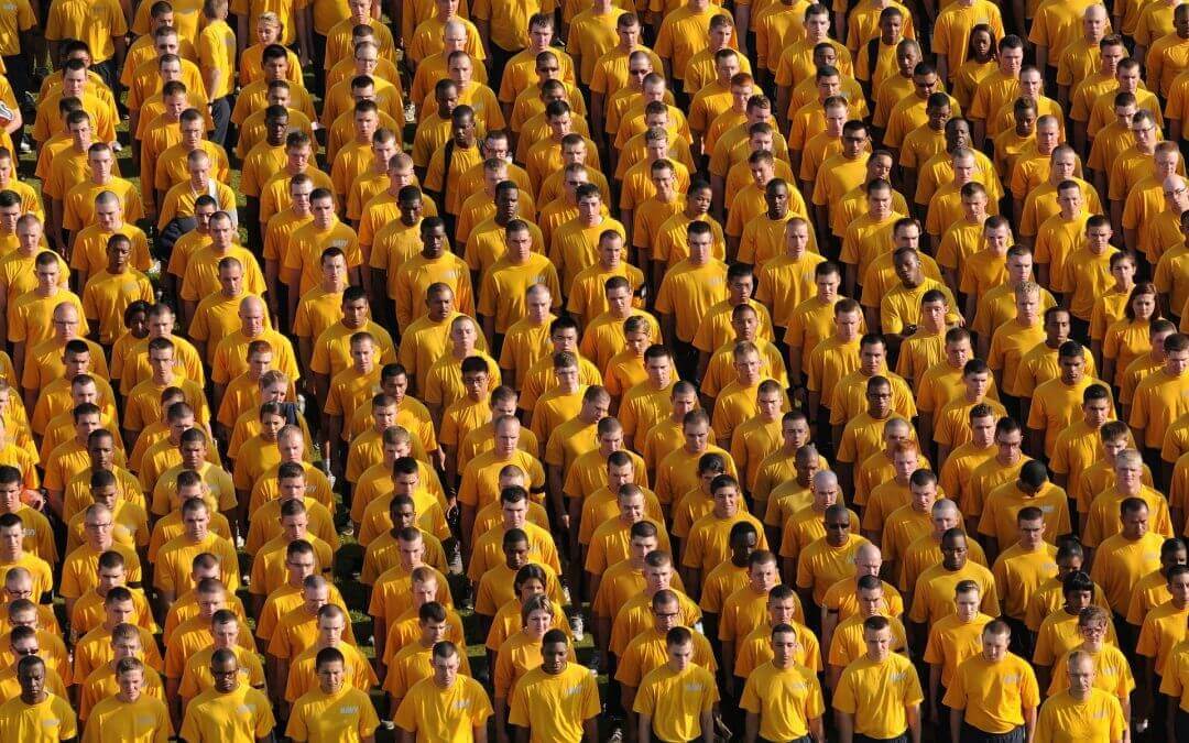 Hundreds of young men in uniformed yellow t-shirts stand orderly in rows, representing a market in need of segmentation.